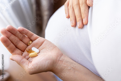 Pregnant woman pills vitamin. Happy smiling woman taking pill with supplement vitamin Omega 3. Vitamin D, E, A Fish Oil Capsules.