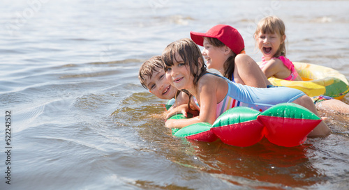 Summer lifestyle a group of children of different ages in swimwear float on air mattress looks like watermelon. Enjoying the little things. spends time in nature in summer