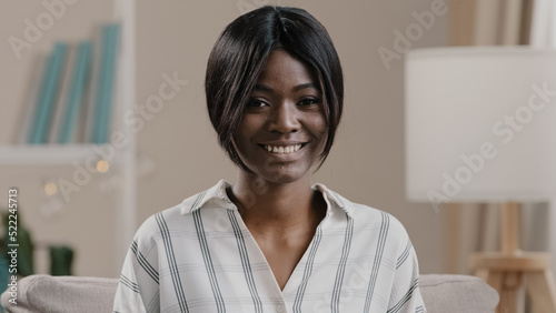Female portrait happy satisfied woman customer smiling looking at camera motivated african american lady student model posing indoor modest cute pretty attractive girl sits in cozy living room on sofa