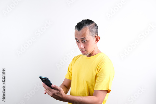 Portrait of Asian Man wearing glasses and casual shirt looks serious with the phone (shocked expression).  © Tyas Indayanti