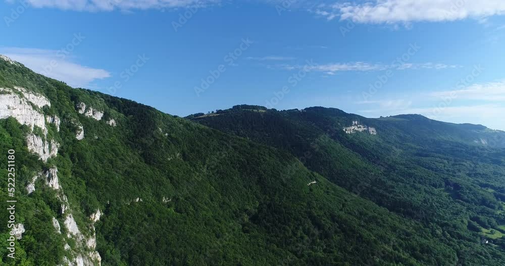 Aerial shot of mountain covered in forest with some fields at the bottom Aerial shot of mountain covered in forest with some fields at the bottom