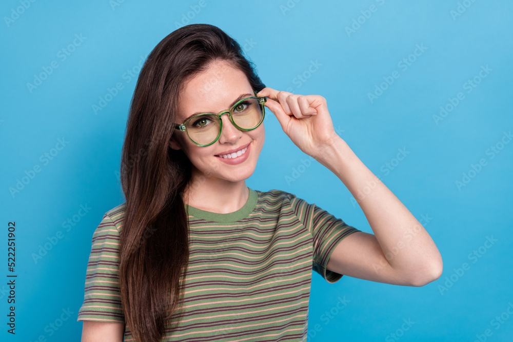 Photo of smart millennial brunette lady wear eyewear green t-shirt isolated on blue background Photo of smart millennial brunette lady wear eyewear green t-shirt isolated on blue background