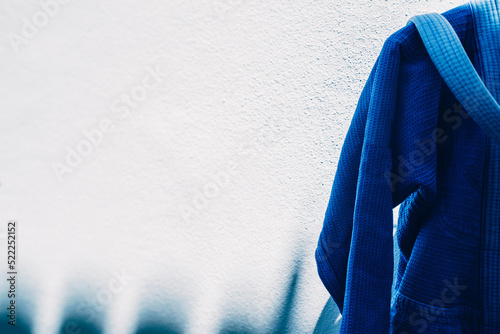 Foto Close up on brazilian jiu jitsu or judo blue kimono uniform hanging next to a wa