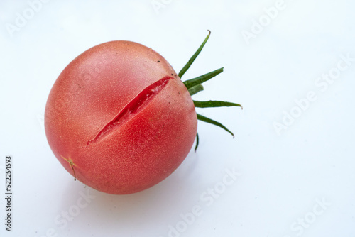 Cracked, juicy, red tomato on white background. photo