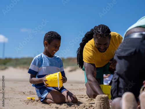 Father and son (8-9) building sand castles on beach
