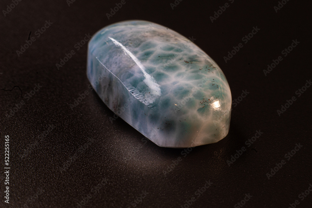 Larimar cabochon on black background macro. Close up picture of oval shaped stone Larimar cabochon on black background macro. Close up picture of oval shaped stone