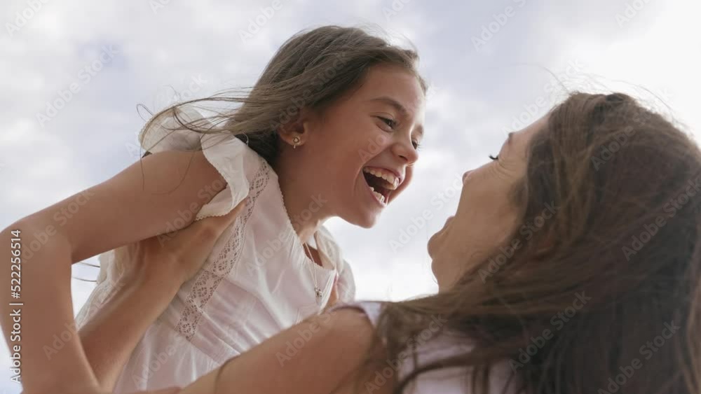 A happy family between mother and daughter holding her in their arms and smiling. A happy family between mother and daughter holding her in their arms and smiling.