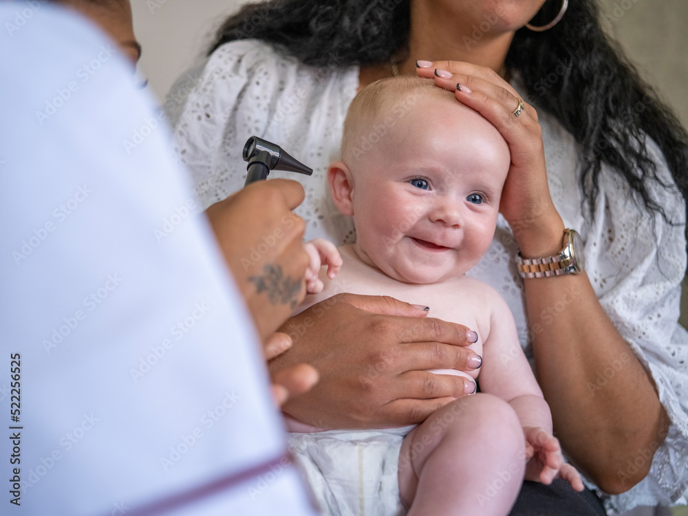 Nurse examining baby girl (2-5 months) with otoscope Nurse examining baby girl (2-5 months) with otoscope