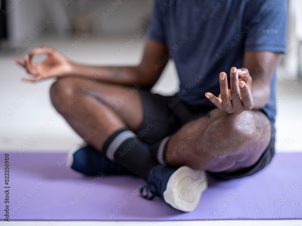 Low section of person in sports clothing meditating on mat