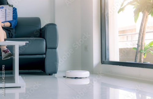 Robot vacuum cleaner cleaning floor in living room. White robot vacuum cleaner for smart home concept. Cleaning robot for cleaning floor. Wireless device. Smart cleaning technology. Household device.