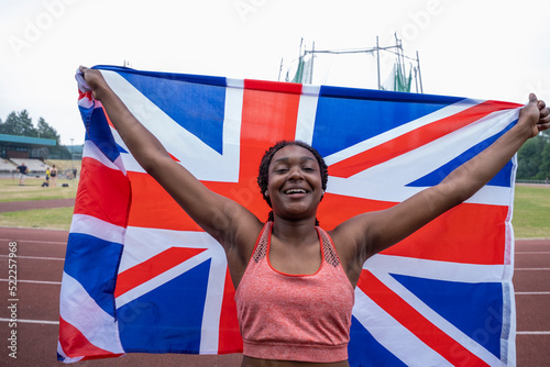 Portrait of smiling athletic�woman with British flag on running track