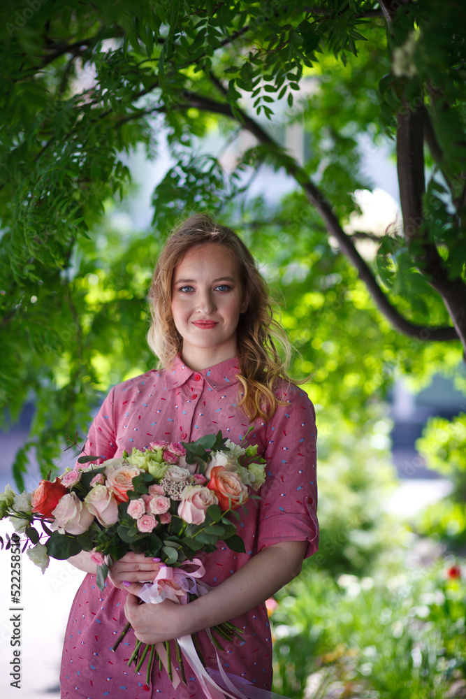 Young happy blonde woman in a pink dress with a large bouquet of flowers walks around the old European city and enjoys life on a summer day, beautiful portraits with a huge bouquet of flowers. Young happy blonde woman in a pink dress with a large bouquet of flowers walks around the old European city and enjoys life on a summer day, beautiful portraits with a huge bouquet of flowers.