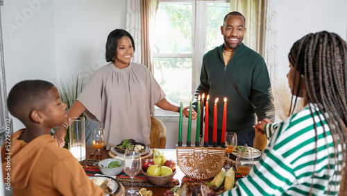 Family with children (8-9, 12-13) holding hands over Kwanzaa meal photo