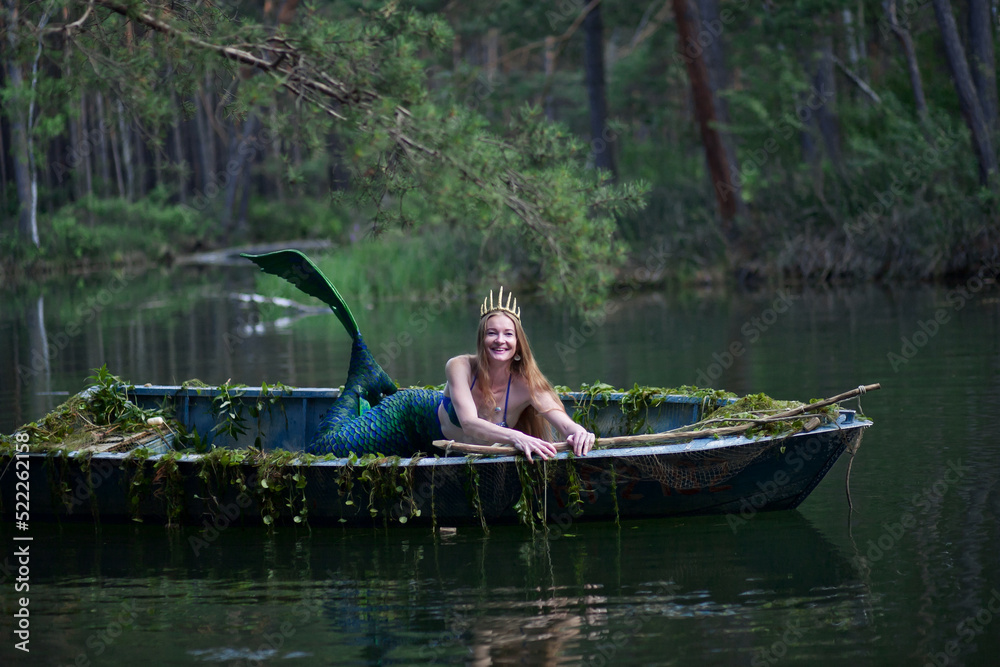 Mermaid story. The little mermaid sits in a boat. Mermaid at sunset ...