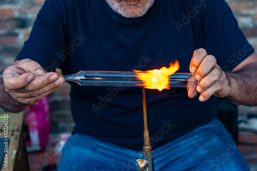 Artigiano del vetro forgia con la fiamma photo