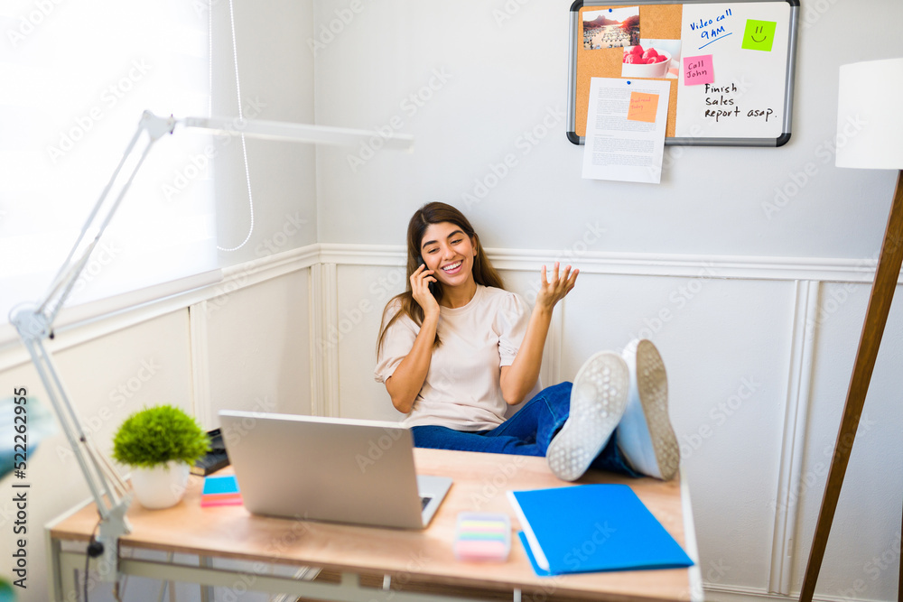 Cheerful busy woman talking on the phone with a client at her office desk Cheerful busy woman talking on the phone with a client at her office desk