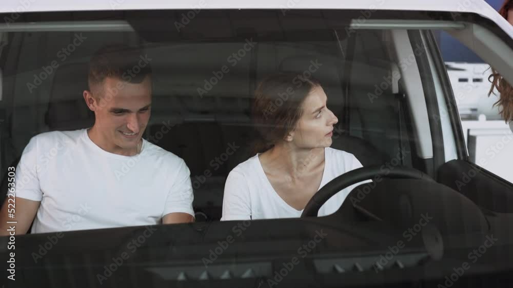 At automobile sales centre. Car salesperson selling new automobile to young family.Beautiful young couple at car showroom choosing a new car to buy