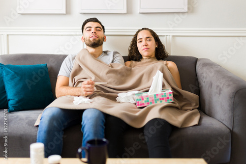 Fototapeta Ill young couple with fever using tissues and recovering from the flu