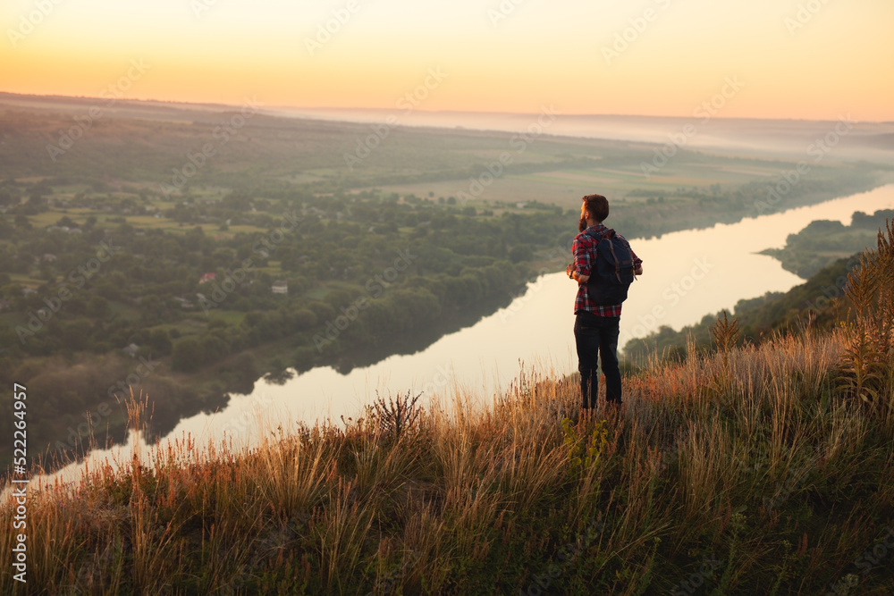 Male traveler admiring river at sunset
