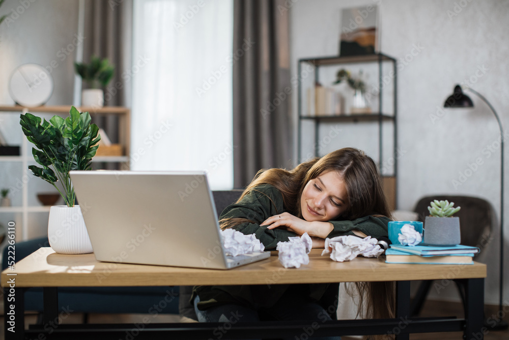 Indoor picture of smiling and tired woman sleeping on the table. Young adult business fatigue woman sleeping on table at office. Business woman tired from working overtime. Indoor picture of smiling and tired woman sleeping on the table. Young adult business fatigue woman sleeping on table at office. Business woman tired from working overtime.