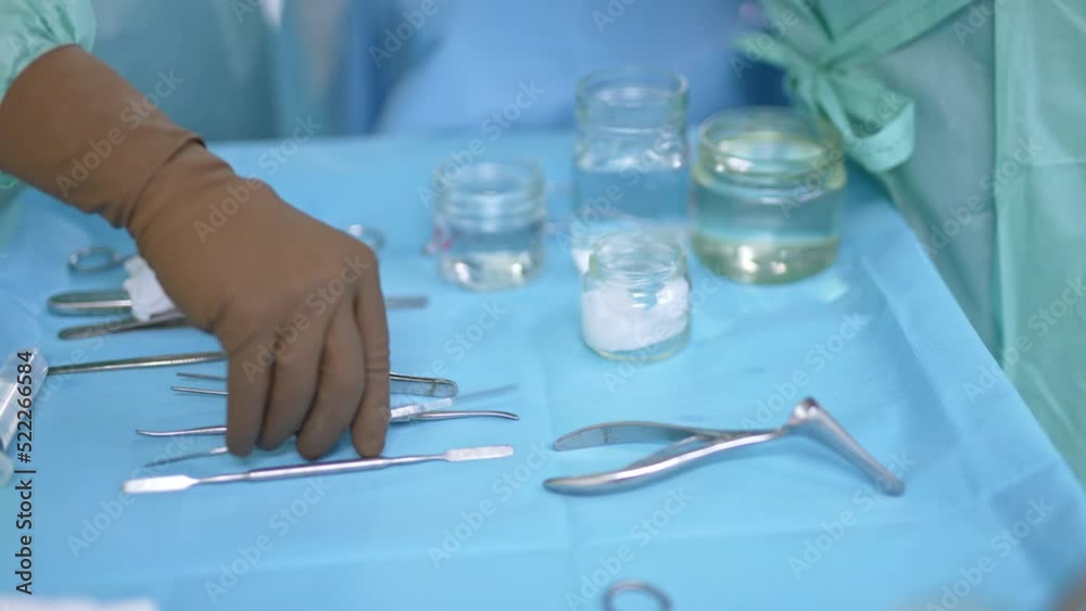 Table with metal instruments and glass jars for nasal operation. Gloved hand of a surgeon takes metal tool from a table and then sponge. Close up. Table with metal instruments and glass jars for nasal operation. Gloved hand of a surgeon takes metal tool from a table and then sponge. Close up.