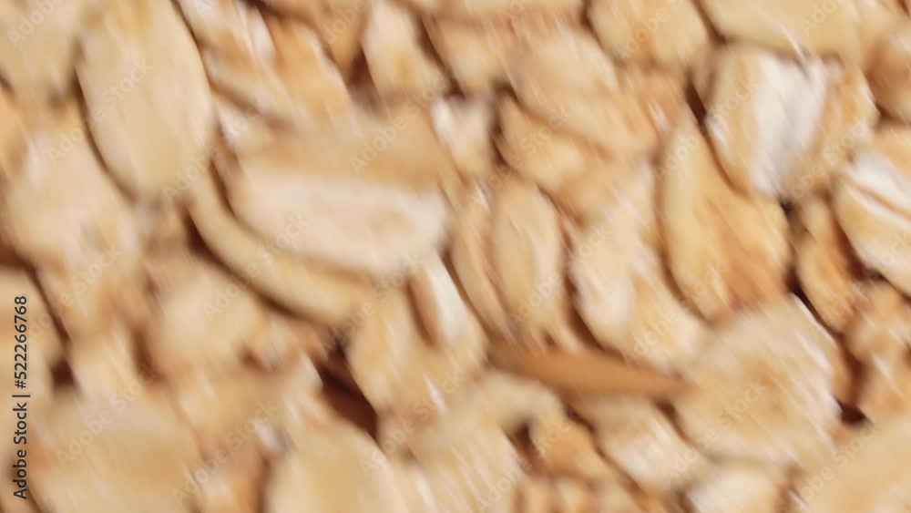 Oat Flakes Background Rotating Counter-Clockwise - Top View, Close-Up. Scattered Dry Oat Flakes. Healthy Breakfast and Diet Eating Ingredients - Angular Rotation Left