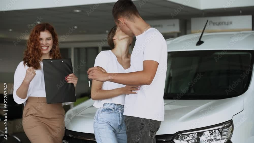 At automobile sales centre. Car salesperson selling new automobile to young family.Beautiful young couple at car showroom choosing a new car to buy At automobile sales centre. Car salesperson selling new automobile to young family.Beautiful young couple at car showroom choosing a new car to buy