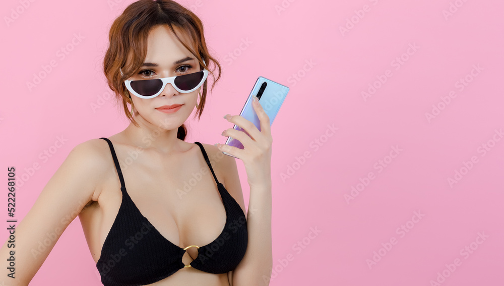 Sexy beautiful women in underwear bikini with sunglass holding smartphone pink background. portrait beautiful female use mobile phone. summer vacation concept.