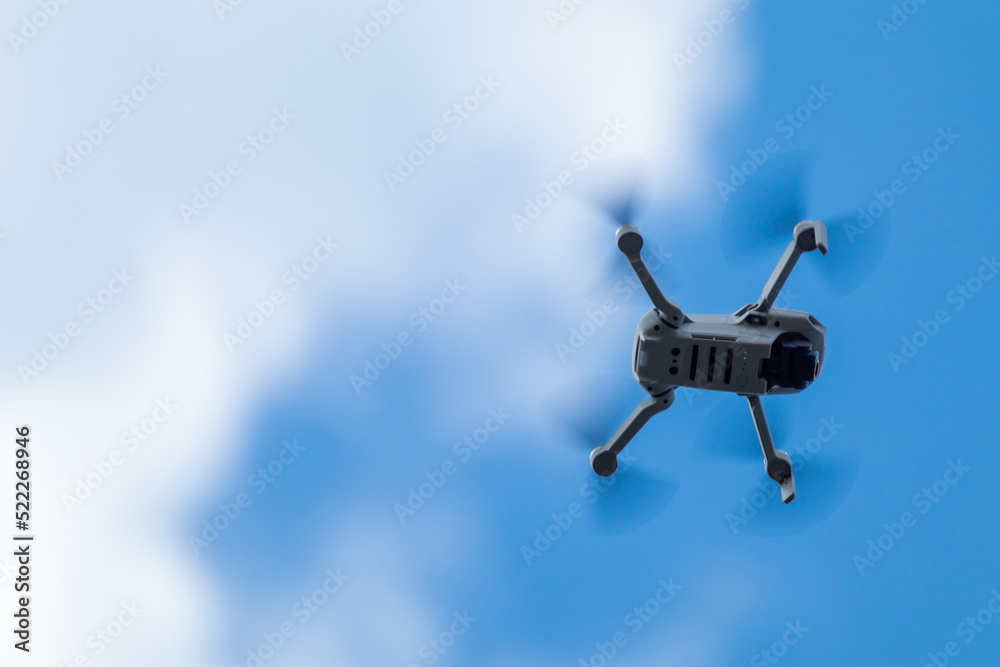 Kharkiv, Ukraine - April 22, 2021: Dji Mavic Mini 2 drone, flying in sunny  day. New quadrocopter device hovering on blue cloudy sky, blurry  background. Bottom view with copy space foto de Stock | Adobe Stock