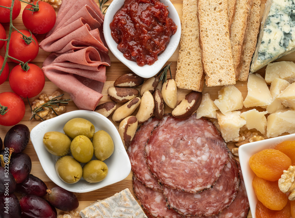 Closeup of appetizer board with cheese, nuts, fruits, toasts and charcuterie