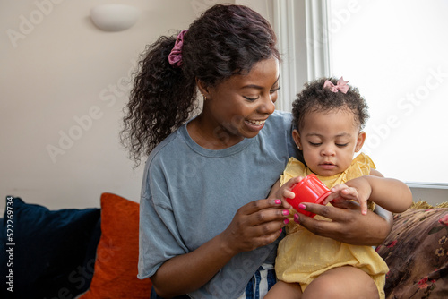 Mother playing with baby daughter (12-17 months) at home photo