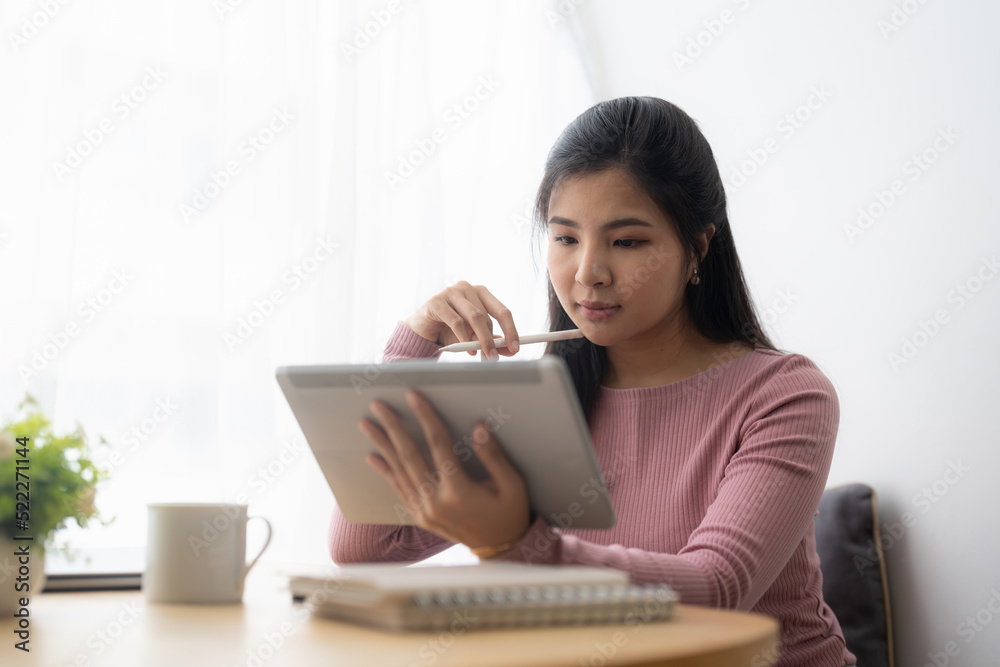 Young asian woman using digital tablet at home. Online learning, home school concept. Young asian woman using digital tablet at home. Online learning, home school concept.