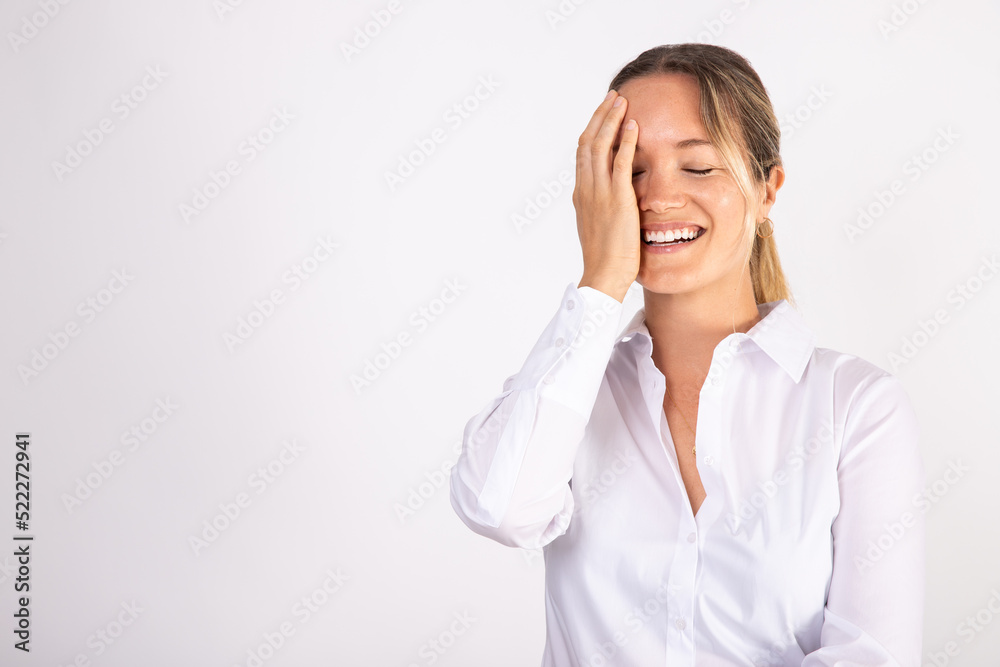 Portrait of laughing young businesswoman covering face with hand. Joyful Caucasian woman wearing white shirt standing and smiling. Successful businesswoman concept Portrait of laughing young businesswoman covering face with hand. Joyful Caucasian woman wearing white shirt standing and smiling. Successful businesswoman concept