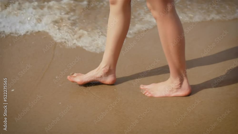 Woman feet walking barefoot by ocean beach and leaving footprints in sand and waves. Freedom lifestyle and traveling in holiday concept Woman feet walking barefoot by ocean beach and leaving footprints in sand and waves. Freedom lifestyle and traveling in holiday concept