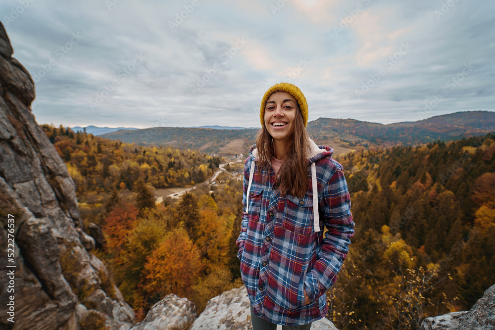 Outdoor portrait young woman hiker in checkered jacket overjoyed emotionally smiling. Inspiring adventure traveling to national park with mountains at autumn