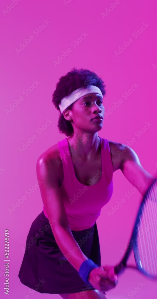 Vertical video of african american female tennis player hitting ball on neon pink lightning Vertical video of african american female tennis player hitting ball on neon pink lightning