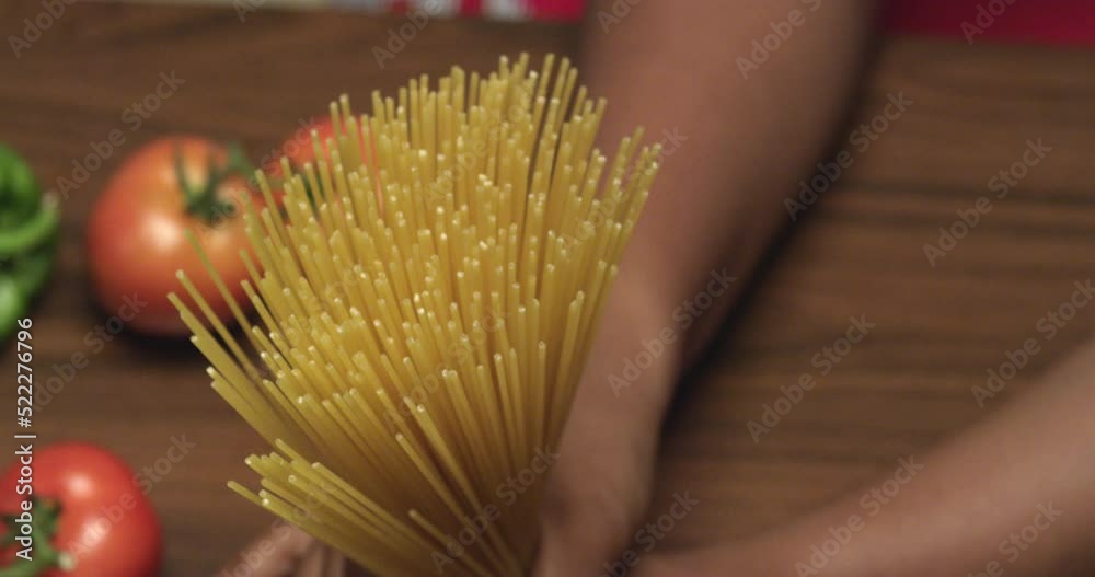 gros plan des mains ouvrant des spaghettis sur la table.