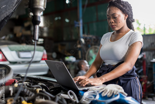 Mechanic using compute for Diagnostic machine tools ready to be used with car. Car mechanic using a computer laptop to diagnosing and check up on car engines parts for fixing and repair