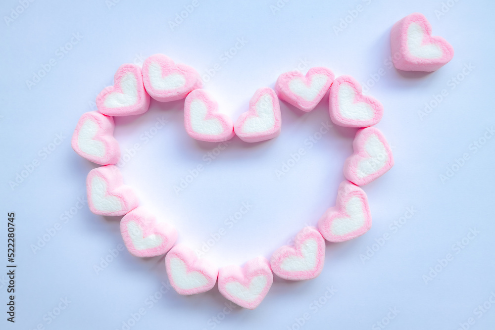 Fototapeta premium Rows of pink and white heart shaped marshmallow candies. Marshmallows in the shape of a heart on background. Fill heart for full of love , small hearts lined up to form a large heart.