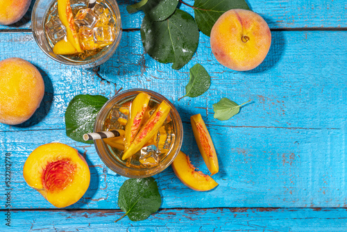 Fototapeta Naklejka Na Ścianę i Meble -  Homemade peach ice tea with ripe fresh peaches on high-colored blue wooden background