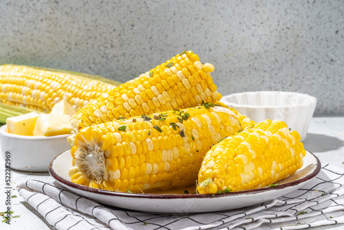 Boiled corn with butter and herbs. Ripe yellow organic cooked corn cobs, on a white kitchen table