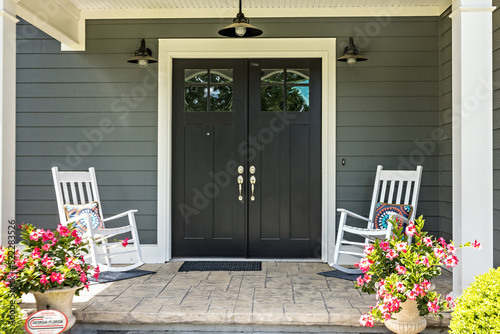 A front porch with two rocking chairs, stamped concrete floors, and double glass doors