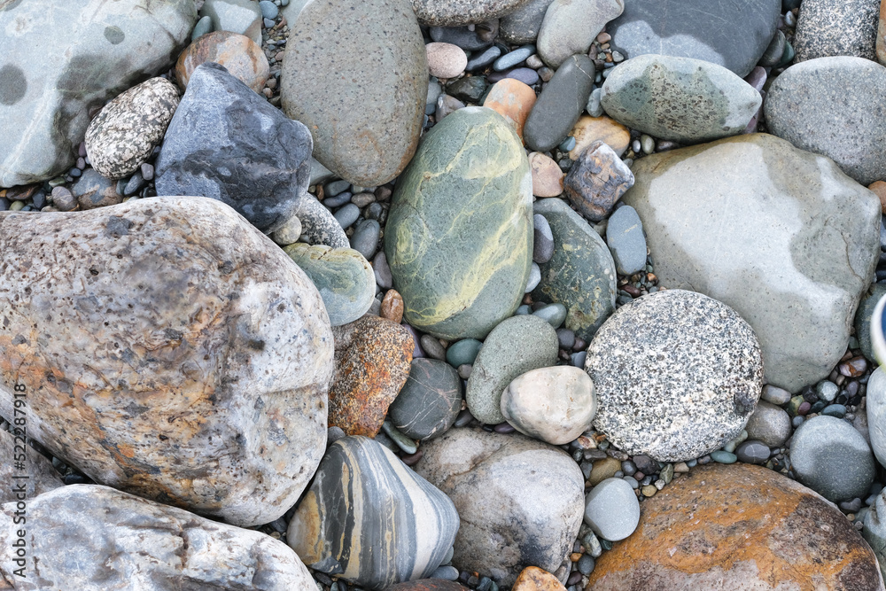 Background of rounded river stones of different colors from the river bank Background of rounded river stones of different colors from the river bank