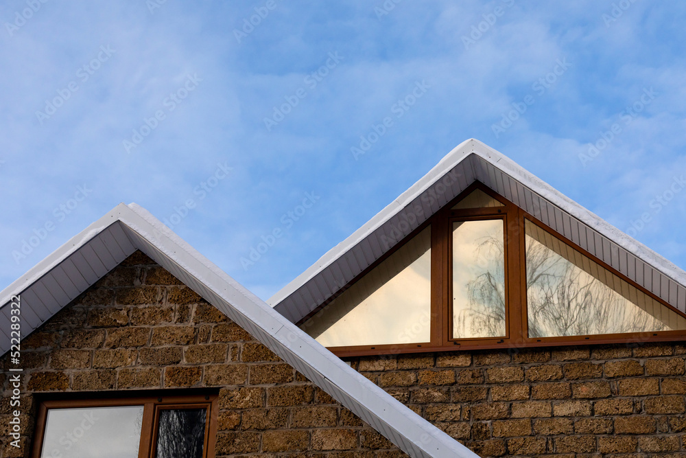 fragment of the roof of house covered with snow against the background of evening sky