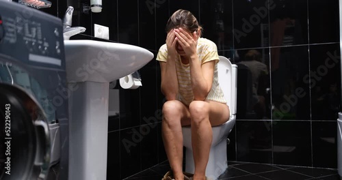 Woman suffers from diarrhea and is sitting on toilet photo