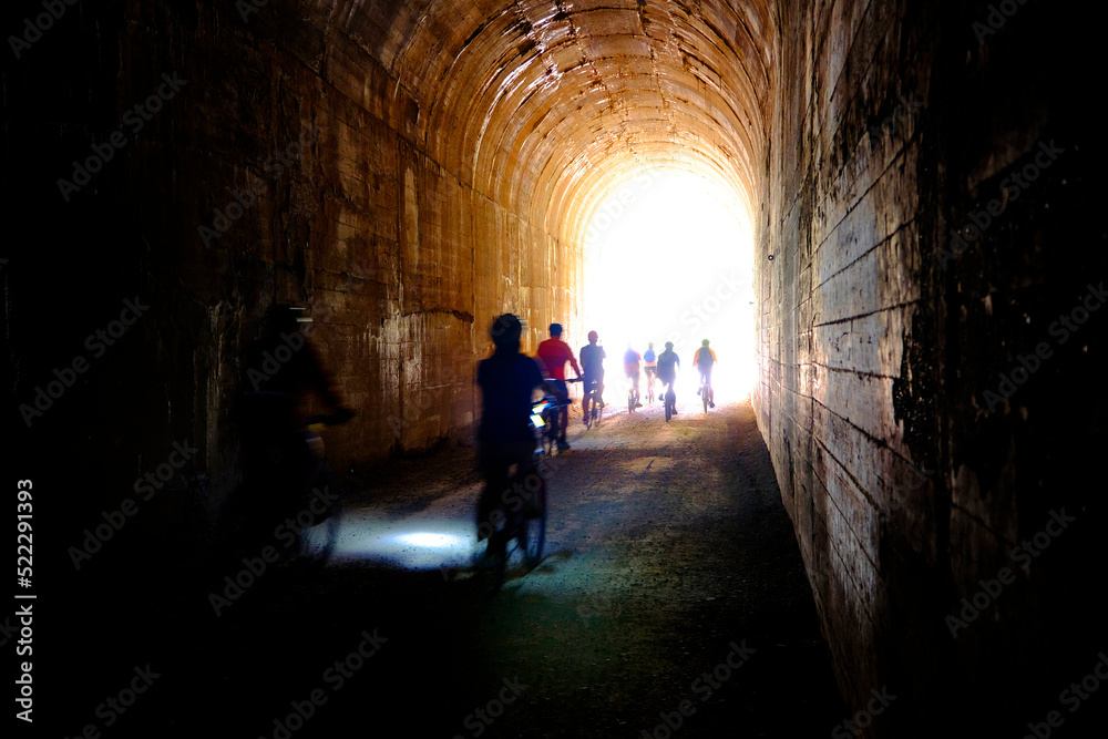 Group of People Biking Through Tunnel with Headlights Hiawatha Trail