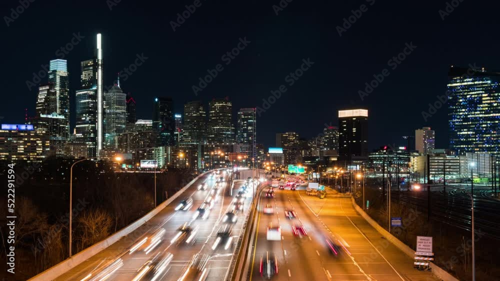 Time-lapse of car traffic transport on multiple lanes highway road, financial district buildings at night in Philadelphia, USA. America transportation, commuter lifestyle, American city life concept