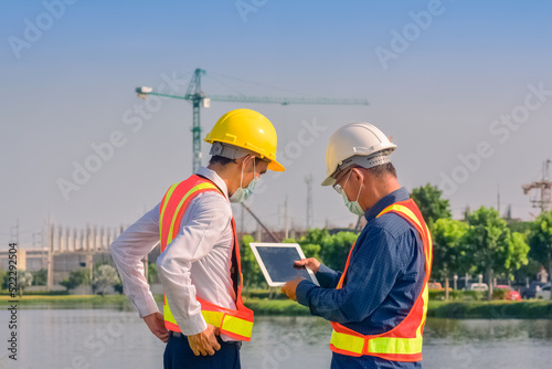 Asian team Construction engineers supervising progress of construction project stand on new factory, Engineering Consulting People on construction site Building inspector.