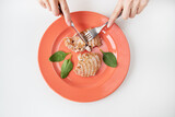 Close-up shot of a juicy delicious grilled tuna steak on a bright coral plate. Delicious and healthy and wholesome food, proper nutrition. The girl is holding a fork and knife.