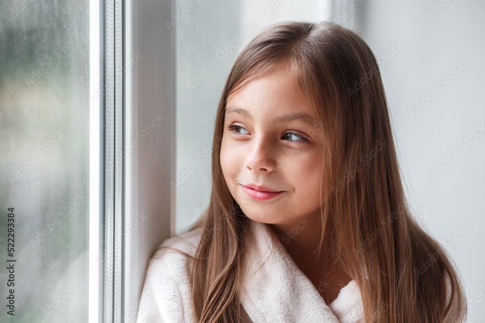 Cute girl sitting on the window and looking at window in room at home. Cute girl sitting on the window and looking at window in room at home.